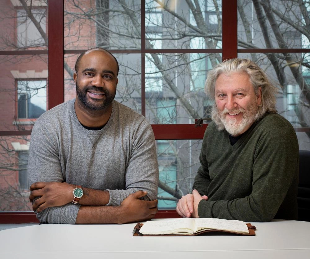 two men sitting at a table with a book